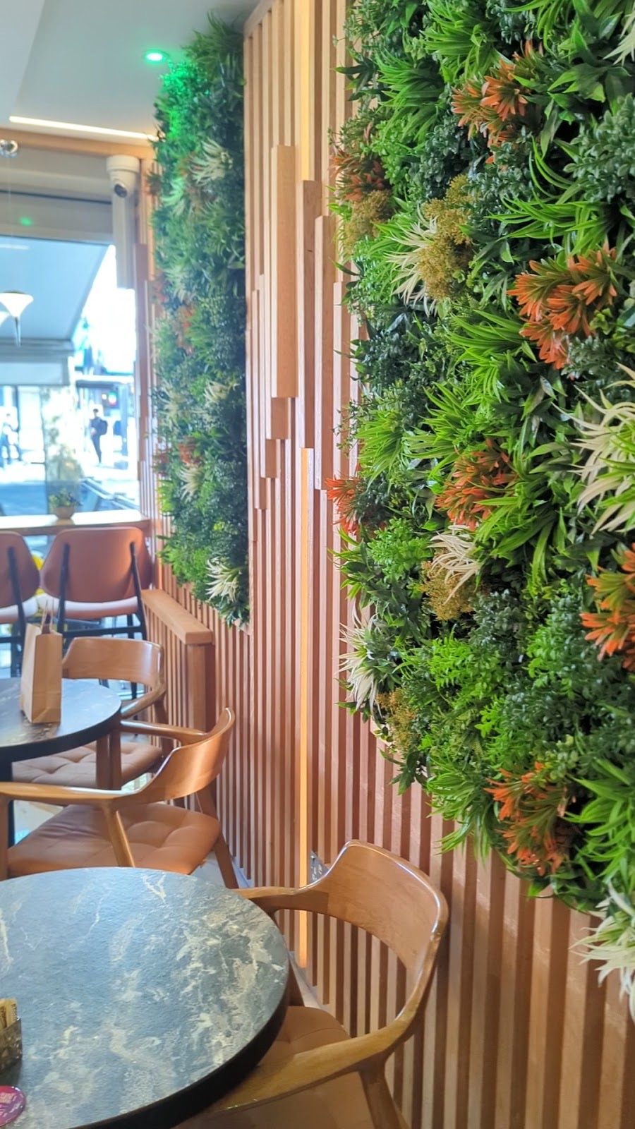 Preserved-foliage feature wall and slatted timber panelling beside a marble table edge.